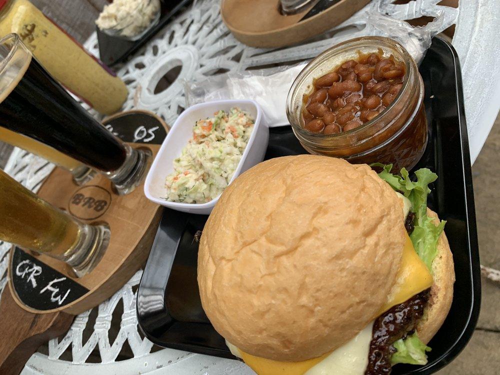 A burger with slaw and beans beside a flight