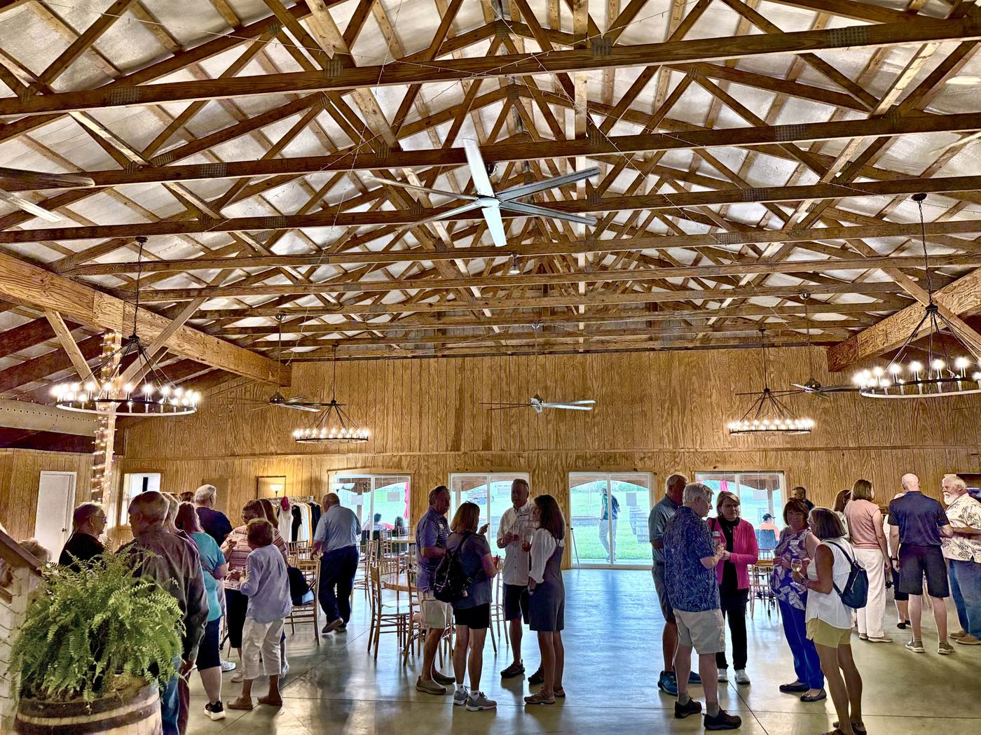 A full barn of guests mingling under the chandeliers