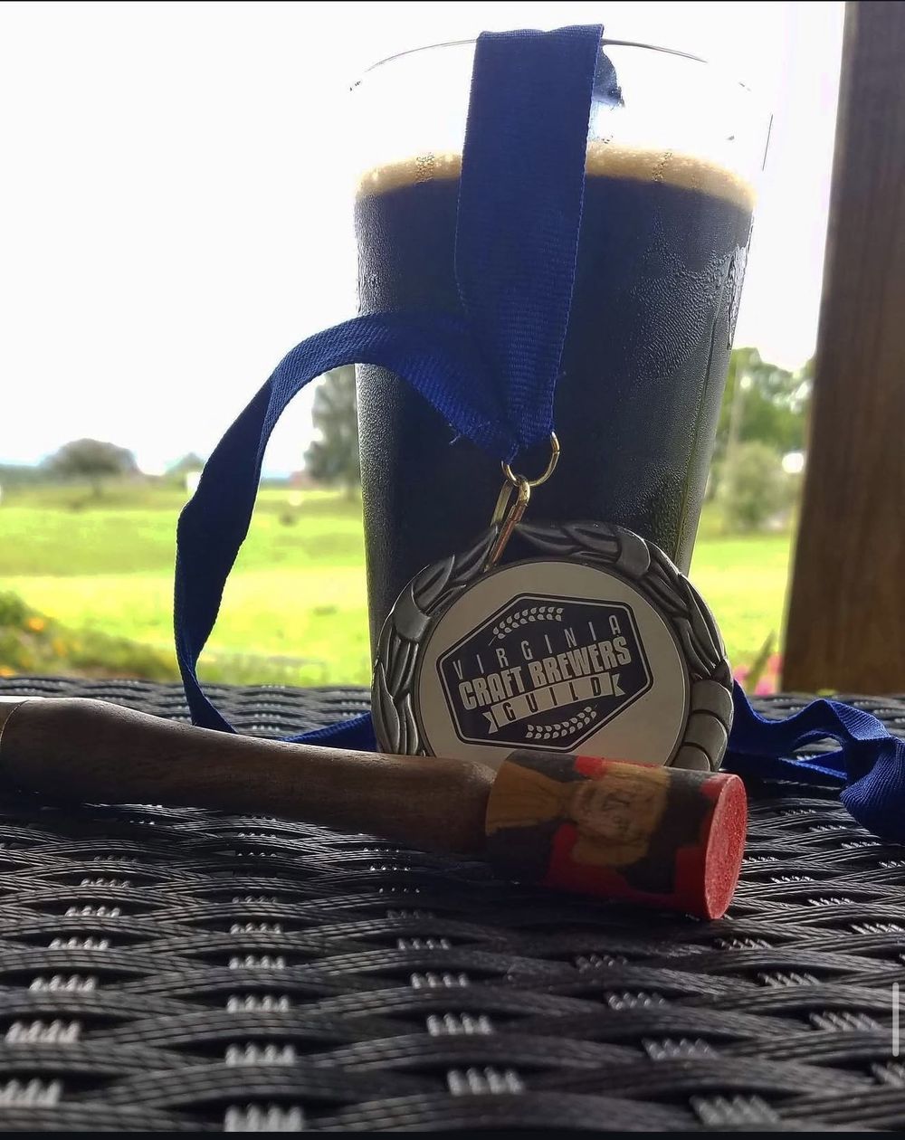 A pint of Oatmeal Stout wearing its Virginia Craft Brewers Guild medal