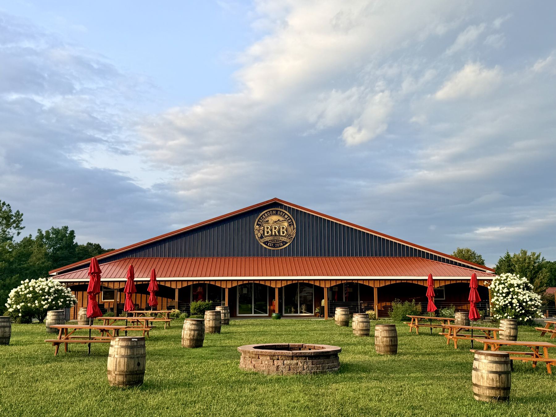 Backroom Brewery at dusk — red roof, barrels, and the fire pit