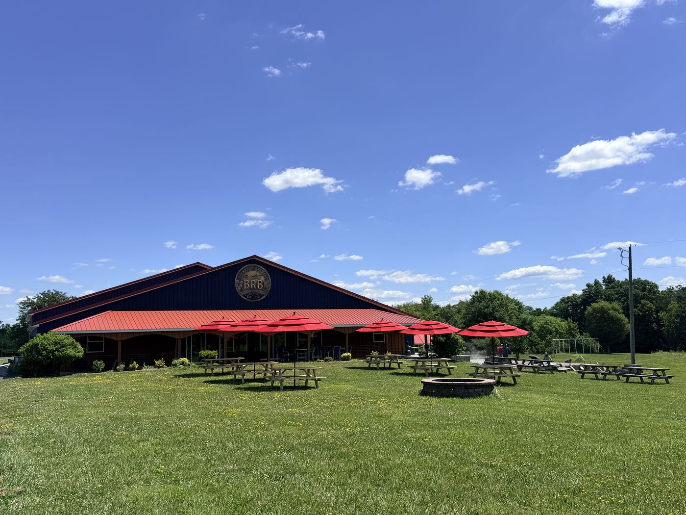 Backroom Brewery under a blue sky with red umbrellas on the lawn