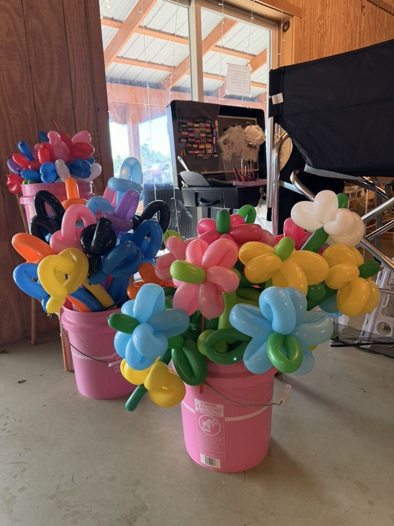 Pink buckets filled with balloon flowers and twisted balloon shapes on the barn floor