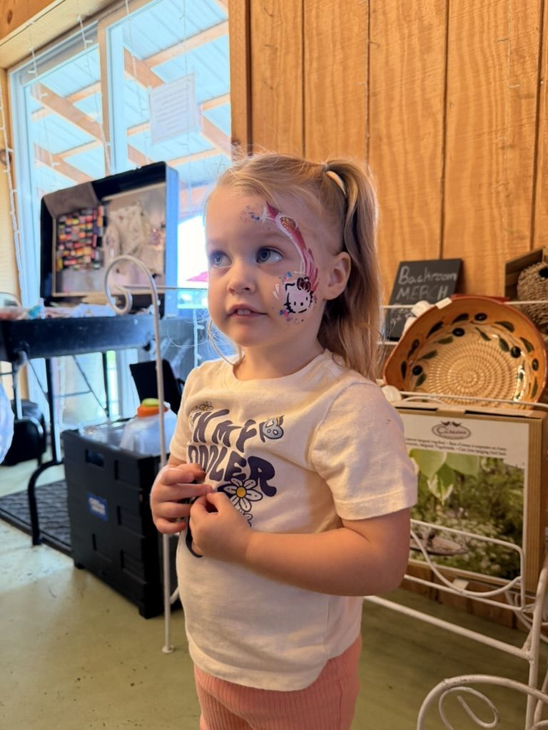 A young girl with a freshly painted pink and white design on her cheek