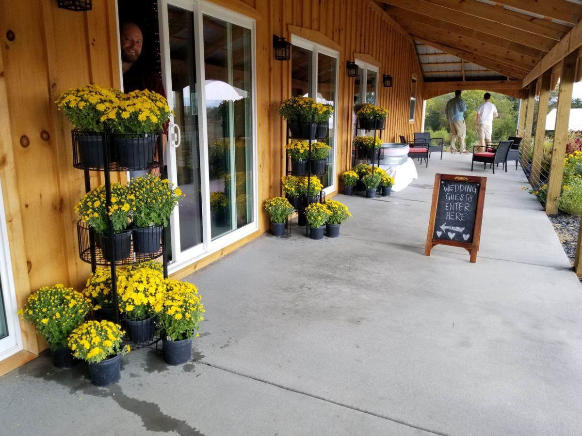 The barn porch lined with yellow mums and a wedding guests sign