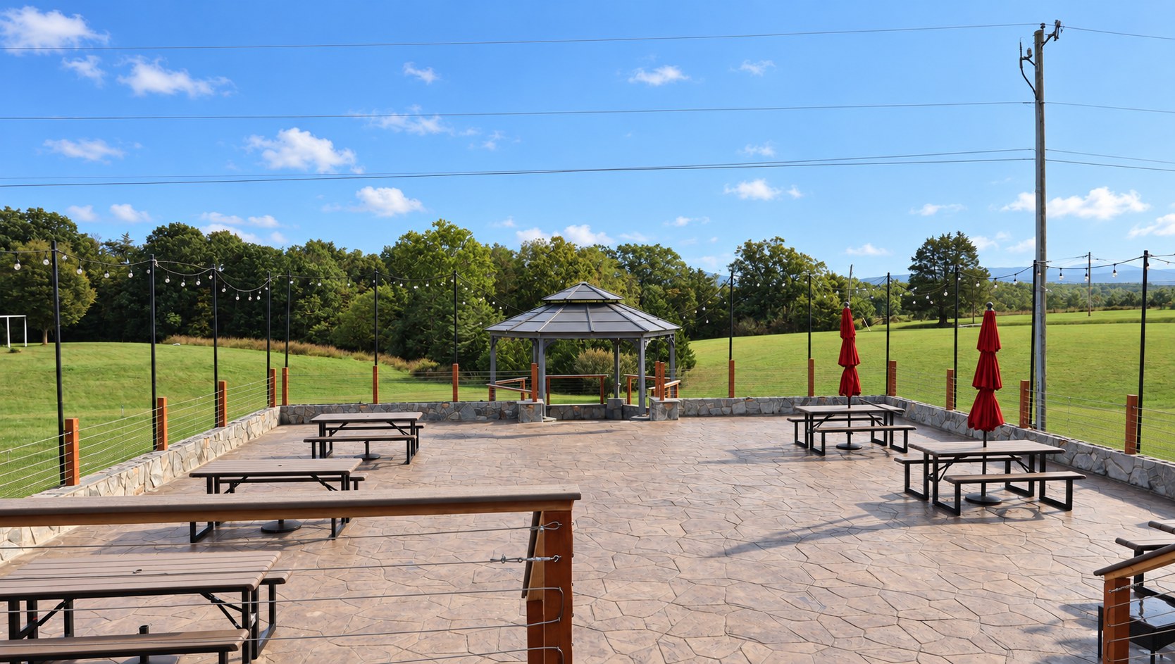 The stamped-concrete gazebo patio with picnic tables, string lights and Blue Ridge views